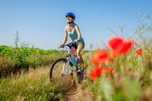 Happy Young Woman Cyclist Riding A Mountain Bicycle In Summer Field. Girl Having Fun Lifting Legs