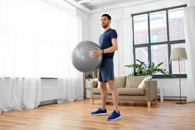 Fitness, Sport And Healthy Lifestyle Concept - Man Exercising With Ball At Home
