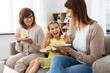 © Syda Productions - family, generation and food concept - smiling mother, daughter and grandmother eating cake at home
