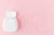 Dental floss on a pink background. The concept of mouth hygiene hygiene, dental health care, dentistry. Minimalism, top view, flat lay.