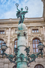 Wall Mural - Sculpture of woman with two wreaths on top of pillar in Vienna Austria with blue sky