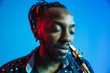 © master1305 - Young african-american jazz musician playing the saxophone on blue studio background in trendy neon light. Concept of music, hobby. Joyful attractive guy improvising. Retro colorful portrait of artist