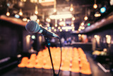 Fototapeta  - Empty event hall: Close up of microphone stand, empty seats in the blurry background