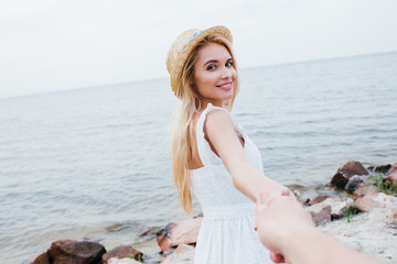 Wall Mural - cropped view of man holding hands with cheerful blonde woman in straw hat