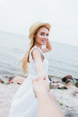 Wall Mural - cropped view of man holding hands with happy blonde woman in straw hat