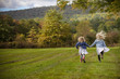 © Cavan Images - sisters running in field with hair wild and free holding hands
