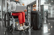 Old lady on disabled carriage working at laptop at airport