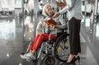 © Yakobchuk Olena - Female worker of airport talking to elderly woman in wheelchair at hall