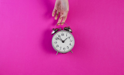 Wall Mural - Female hands hold retro alarm clock on pink background