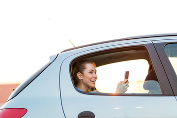 Wall Mural - Young woman with smartphone on the back seat of a car