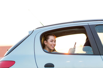 Wall Mural - young woman with smartphone on the back seat of a car
