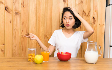 Asian young woman having breakfast milk surprised and pointing finger to the side