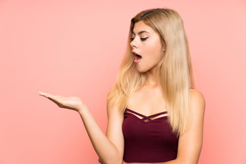 Teenager girl over isolated pink background holding copyspace imaginary on the palm