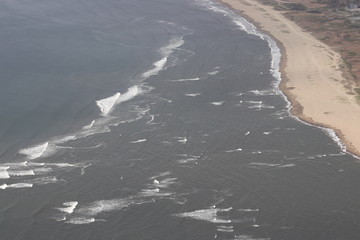 Aerial view of the sand sea beach and shallow water with waves.