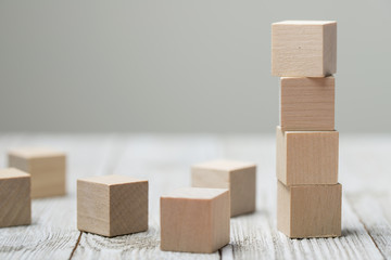 Four wooden toy cubes arranged in vertical on white grey wooden background