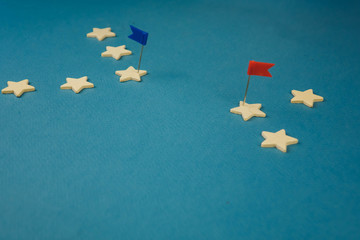 wooden cubes in the form of stars lined up in a chain and one star with a red flag, the star with the flag symbolizes the commander