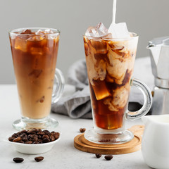 Wall Mural - Summer drink iced coffee or caffe latte in a glass with milk and coffee beans.