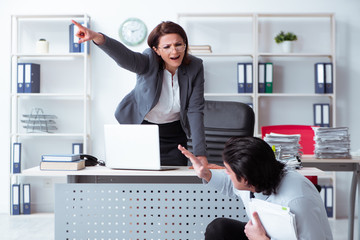 Old female boss and young male employee in the office  