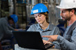 © auremar - male and female industrial workers looking at laptop