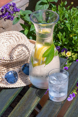 Wooden garden table with carafe and glass of water and leisure summer time accessories