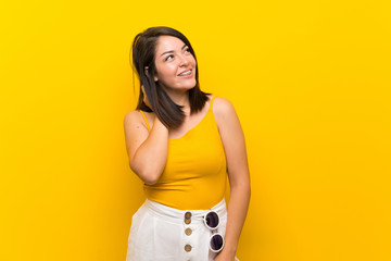 Young Mexican woman over isolated yellow background thinking an idea