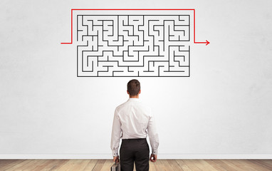 Businessman in doubt looking to a maze and searching the way out