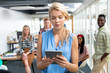 © WavebreakMediaMicro - Businesswoman using digital tablet while diverse colleagues standing in background at office