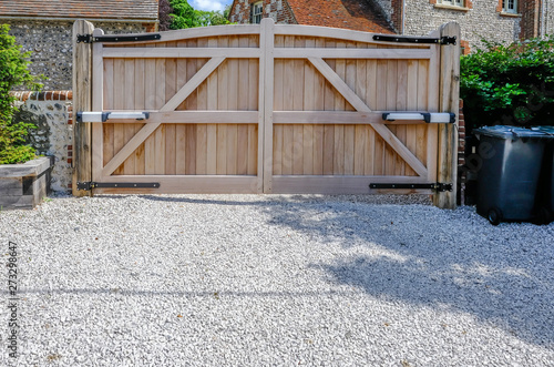 Fotomural Large wooden entry electric gates with stone driveway.