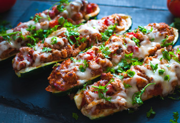 close-up of stuffed zucchini boats with ground beef, spicy tomato sauce, cheese and fresh parsley, o