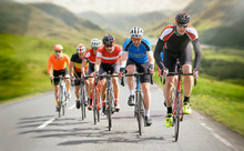 Cyclists Out Racing Along Country Lanes In The Mountains In The United Kingdom.