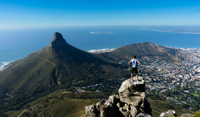 a hiker looking out over cape town from the top of table mountain