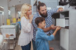 © Ihor - Mature couple and their young son examining childrens desk on sale at furniture store. Happy family shopping for furniture together