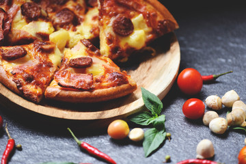 Pizza slice on wooden tray and tomato chilli basil leaf on the dark / delicious tasty fast food italian traditional pizza cheese