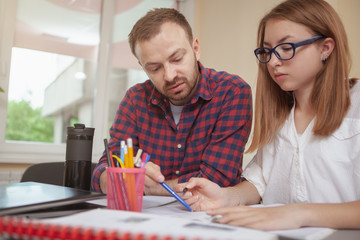 Mature bearded man tutoring his teenage female student, copy space. Lovely teen girl working on a study project with her teacher. Intelligence, knowledge concept