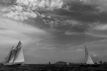 Wall Mural - Vintage yachts race in Barcelona. Old ships and boats in the sea. Black and white photos of nautical sports in the ocean. Regatta in mediterranean sea. Sails, mast, sheet, canvas in the sky. Holidays