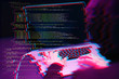 © nuclear_lily - Hacker working with laptop in dark room with digital interface around. Image with glitch effect.