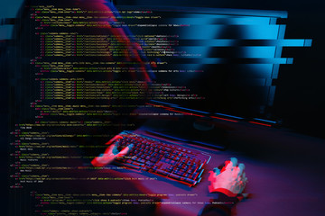 Hacker working with computer in dark room with digital interface around. Image with glitch effect.