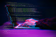 © nuclear_lily - Hacker working with laptop in dark room with digital interface around. Image with glitch effect.