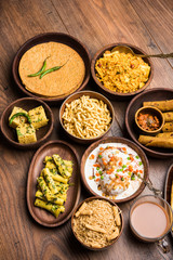 Group of Gujarati snacks like jalebi-fafda, thepla, khaman dhokla, aloo bhujiya, khandvi,khakra, dahi vada, gathiya with hot tea