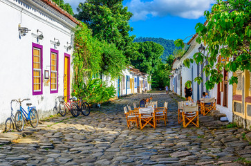 Fototapete - Street of historical center  with tables of restaurant in Paraty, Rio de Janeiro, Brazil. Paraty is a preserved Portuguese colonial and Brazilian Imperial municipality