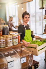 Wall Mural - Woman working in a bulk food store, crate of salads in her hands