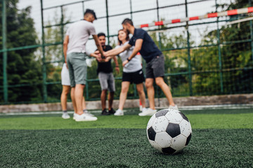 Wall Mural - Close up of football ball  on green field.. Players going  to playing together..