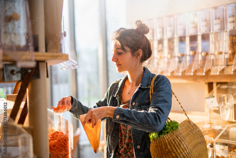 Beautiful young woman shopping in a bulk food store. - obrazy, fototapety, plakaty 