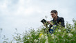 © Anton Dios - Side view of young handsome man in glasses and warm jacket reading book in open space on background of green hills