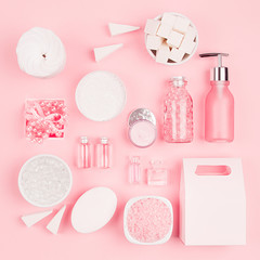 Cosmetic products for bathroom, health and hygiene in modern girlish style - decorative heart, soap, bath salt, essential oil, cream, towel, perfume, pearls, gift box on pink background, square.