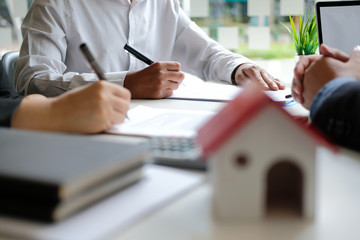 couple buying renting house signing mortgage contract agreement with realtor real estate agent.