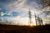 Fototapeta  - electric transmission lines in the field near the city in the rays of a beautiful bright yellow sunset