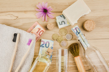 Set of different zero waste beauty products on wooden background with euro money bank notes around them, zero waste sustainable lifestyle true cost concept. 