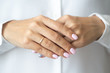 © cherry_d - Close-up photo of elegant light pink manicure over white shirt background, tender women's hands with perfect nails, spa and care