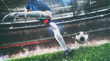 Fototapeta Sport - Football scene at night match with player kicking the ball with power